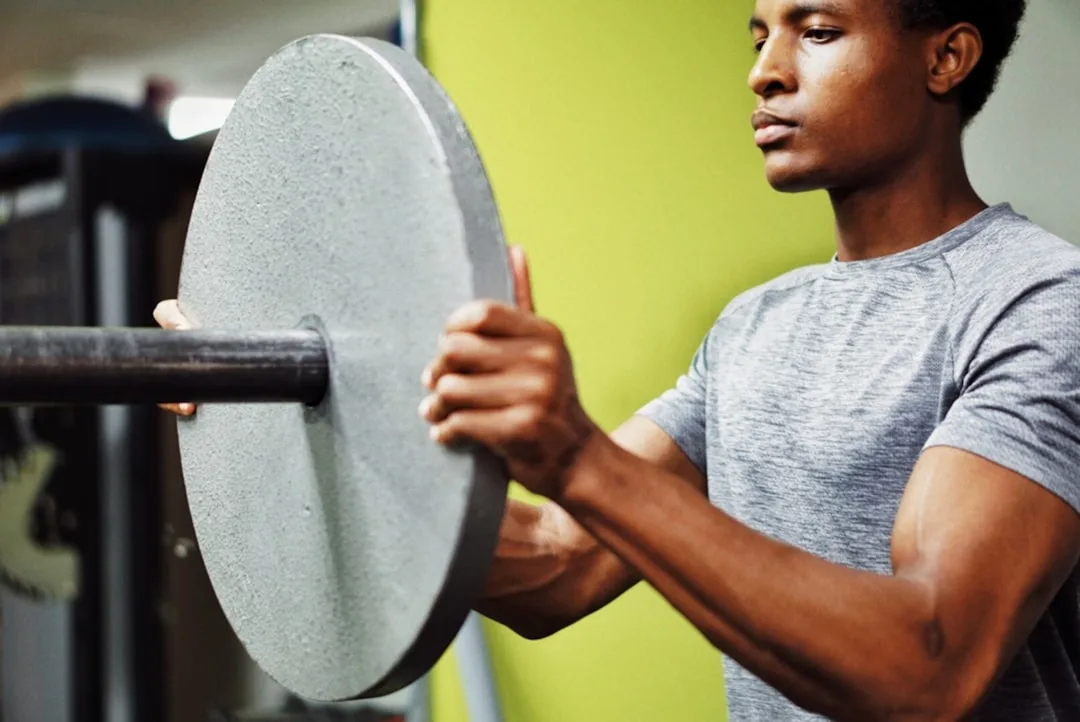 A man loading a weight plate in the gym
