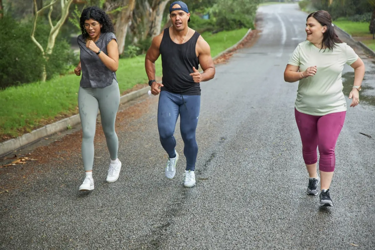 Three friends out for a run together on a tree-lined road