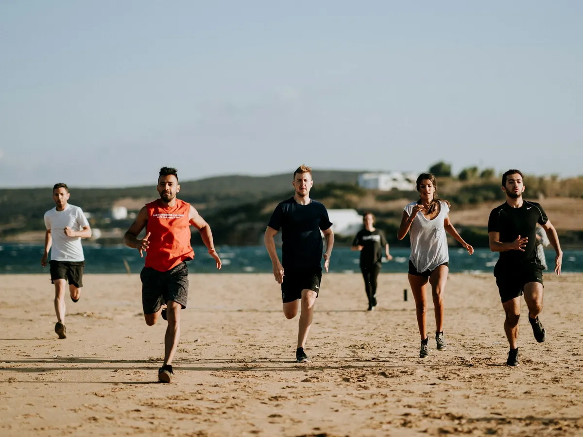 Six people running together along a beach