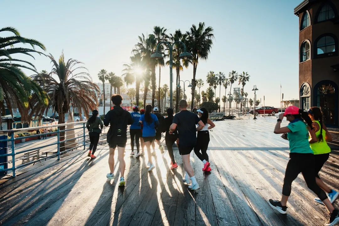 A group of friends running together along a seafront at sunrise
